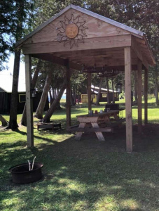 A wooden pavillion with a picnic table underneath